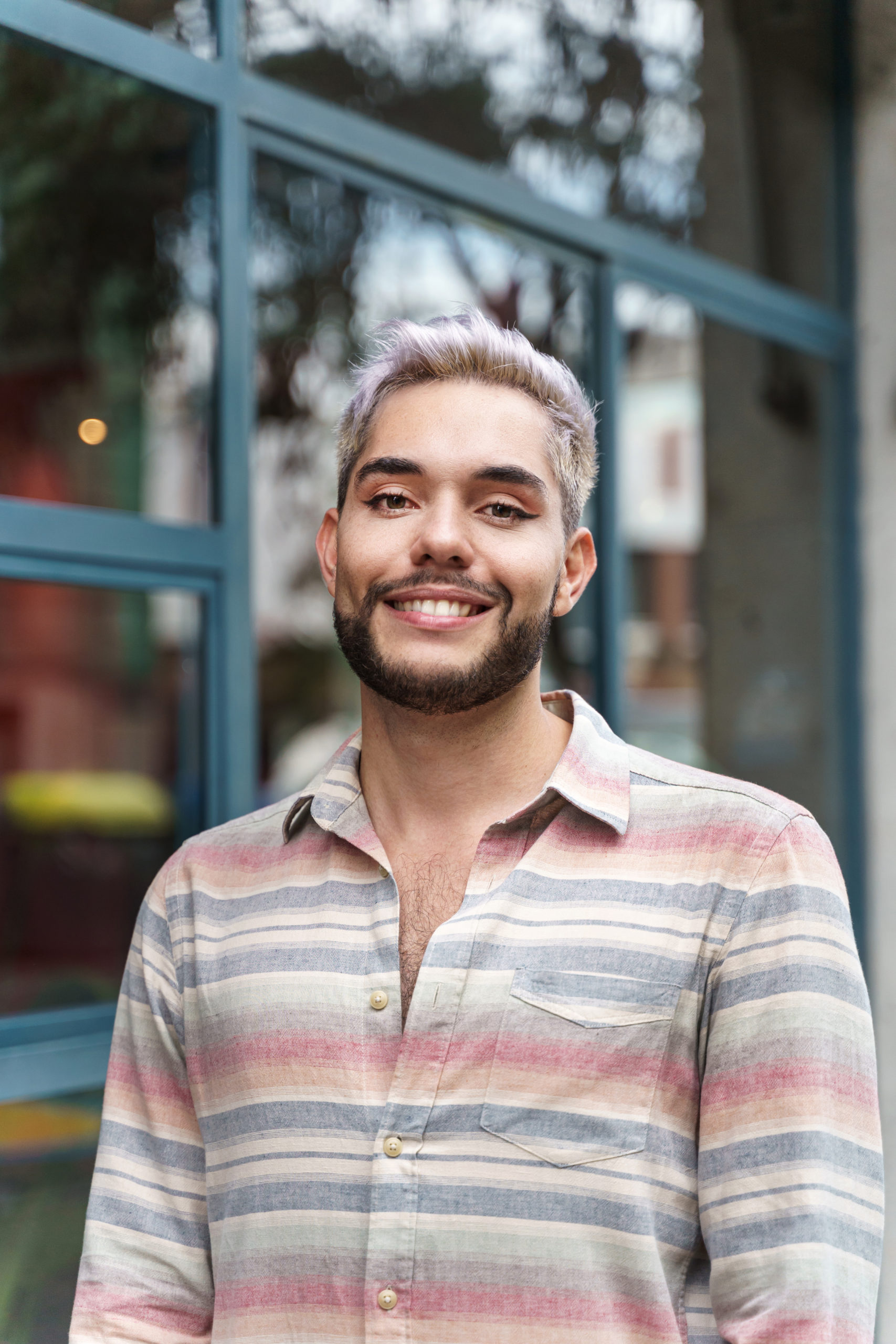 Portrait of happy confident young man with trendy casual wear looking to the camera. Gay man with make up in his face